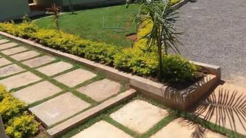 A residential property with a paved driveway, a lawn, and a house with a tiled roof.