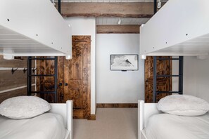 Ein Zimmer mit zwei Betten, Holztüren, einem gerahmten Bild an der Wand und einer Decke mit freiliegenden Balken.