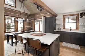 A modern kitchen with a large island, bar stools, and a view of the outdoors.