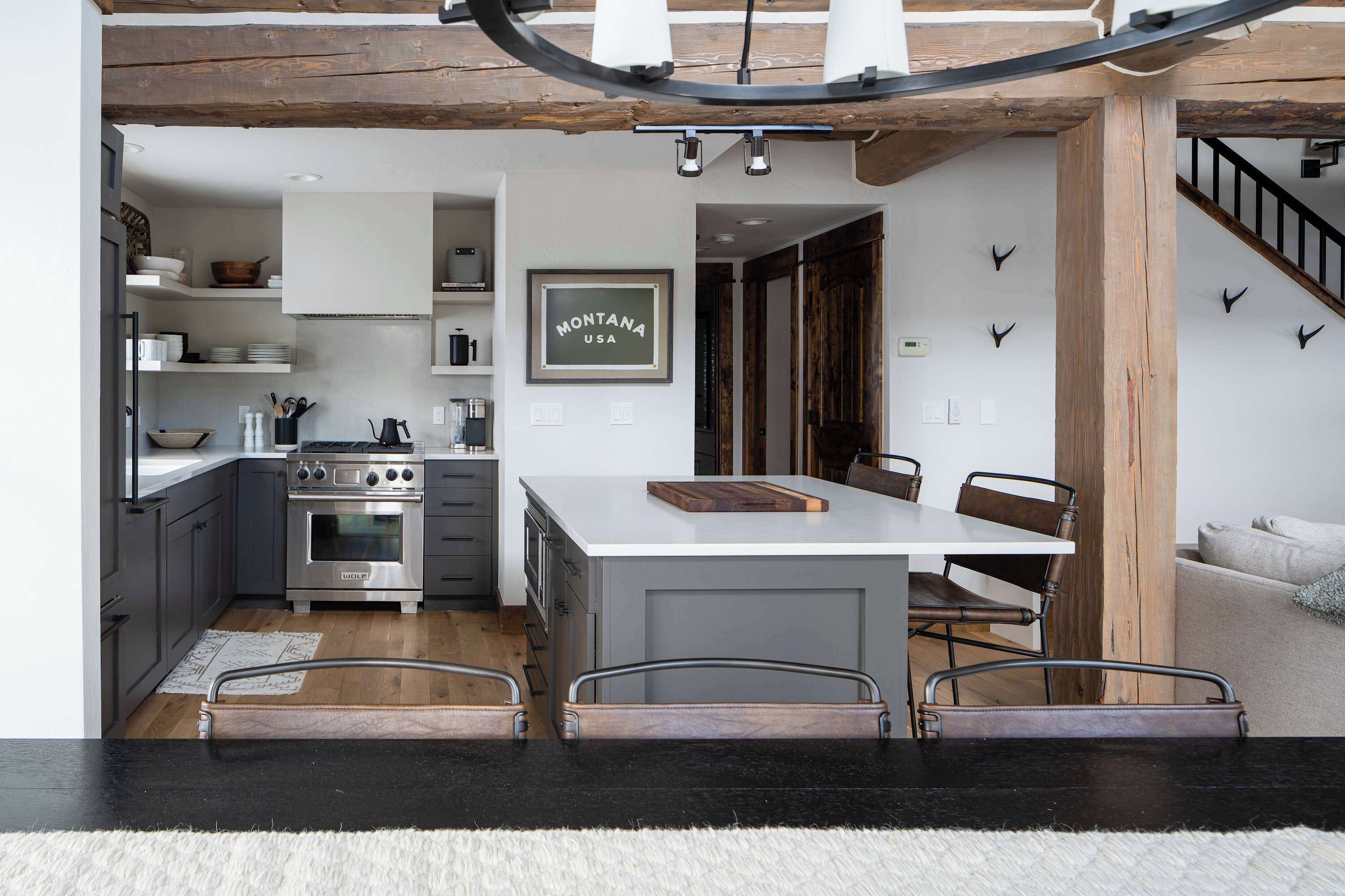 Una cocina moderna con una isla central, electrodomésticos integrados y un techo rústico.