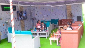 Een zithoek met stoelen, een televisie en een Heineken bord.