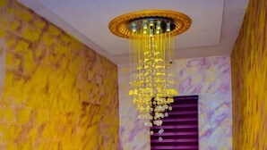 Een marmeren trap met een metalen leuning, een paars raam en een decoratieve kroonluchter.