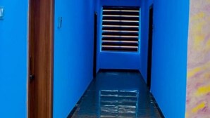 Een gang met blauwe wanden, een houten deur en een raam met horizontale zonwering.