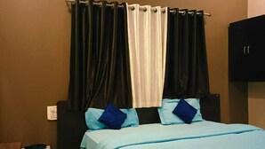 Una camera da letto con un letto, tende, condizionatore e un armadio.