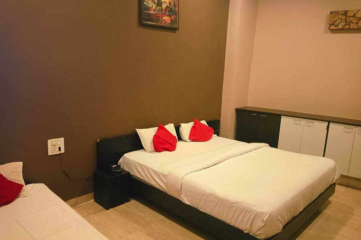 A hotel room with a bed, a bedside table, a wardrobe, and a wall-mounted artwork.