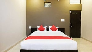Una camera d'albergo con un letto, una porta e un punto luce a parete.