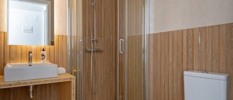 A modern bathroom with a glass-enclosed shower, a white sink, and a toilet.