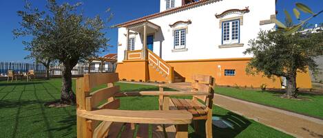 A white building with orange trim, a staircase, and a wooden bench in front.