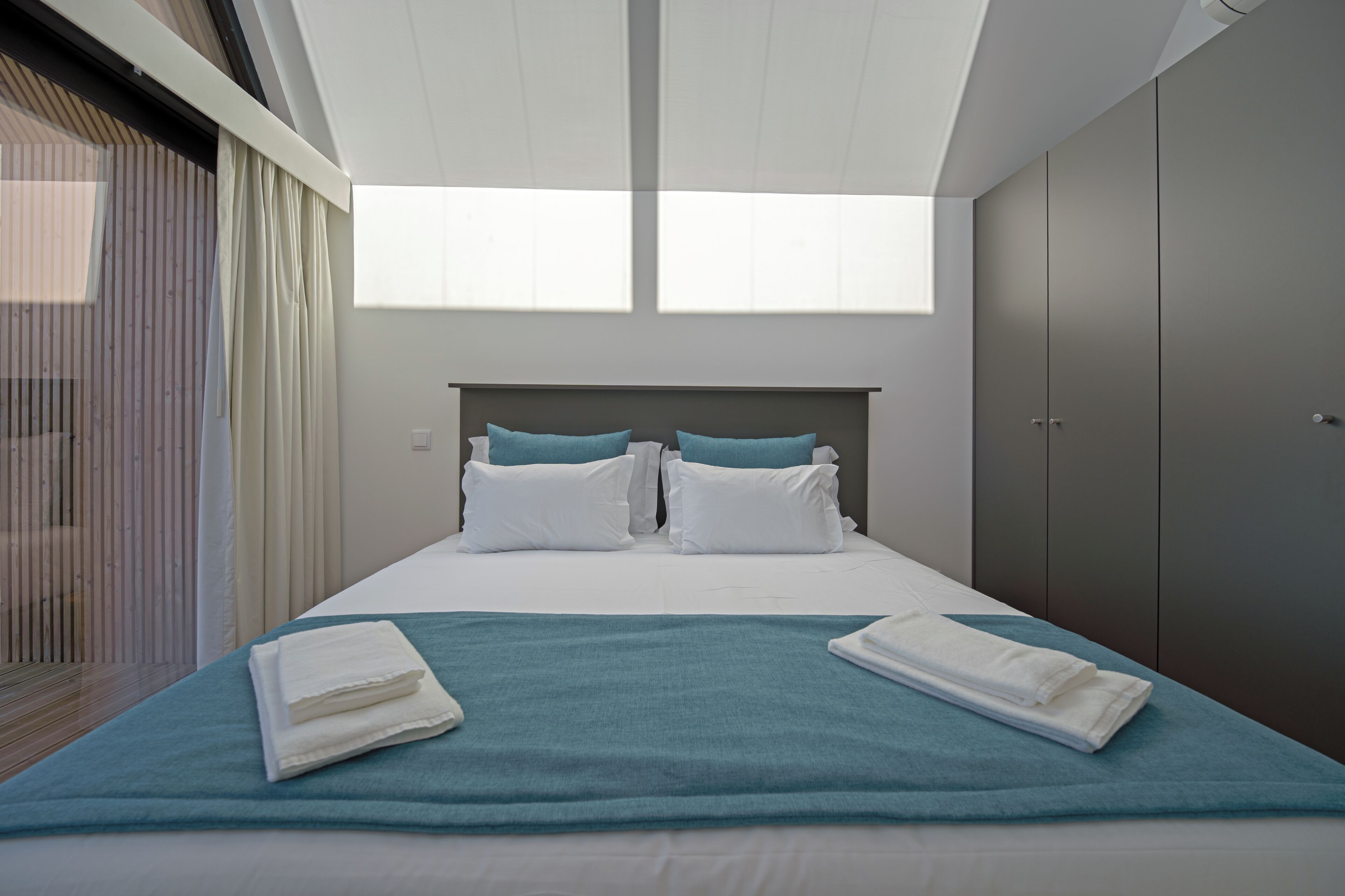 Ett modernt hotellrum med en stor säng, utsikt mot himlen genom taket och en garderob.