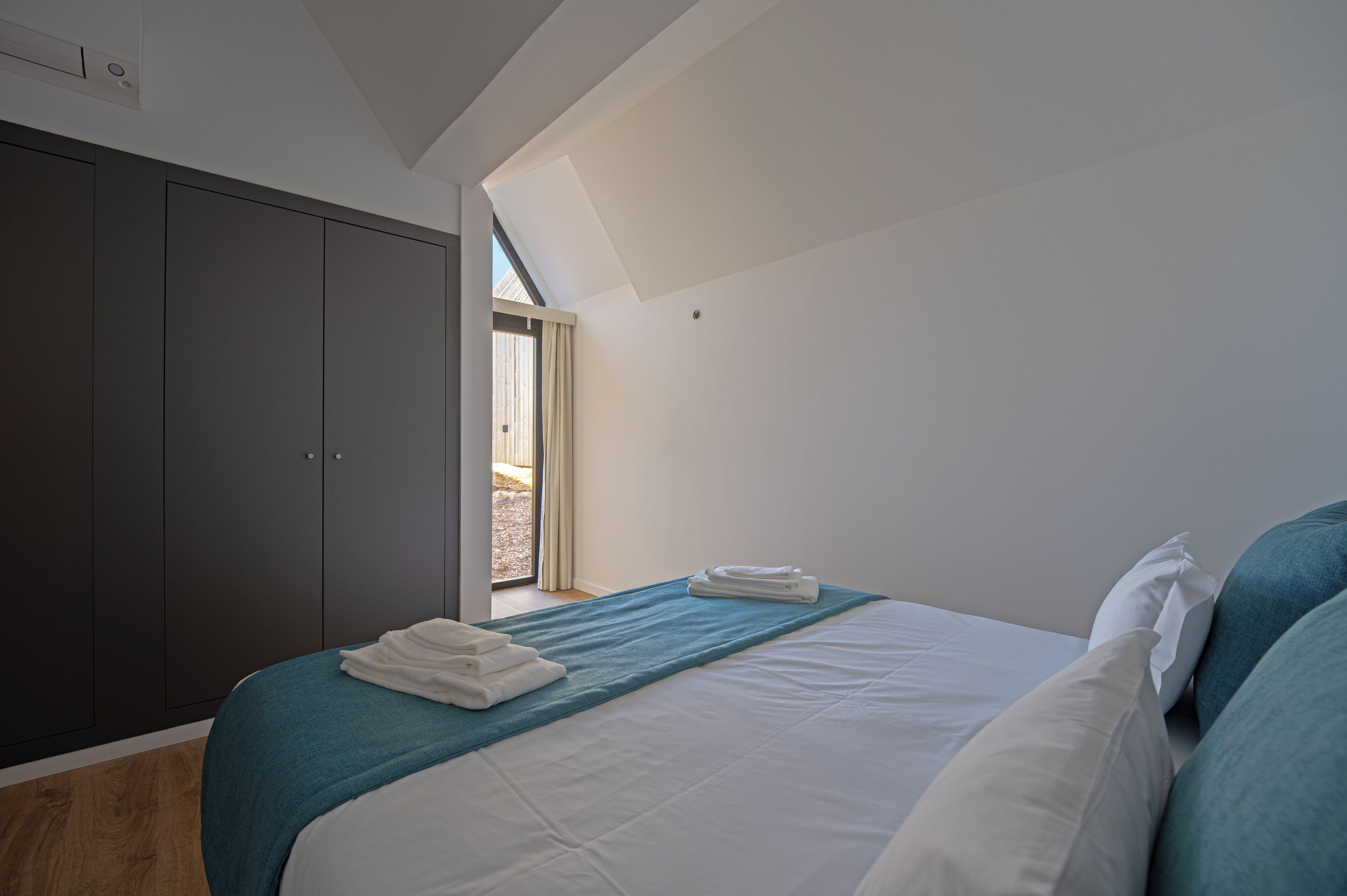 A bedroom with a bed, a window, a wardrobe, and a skylight.