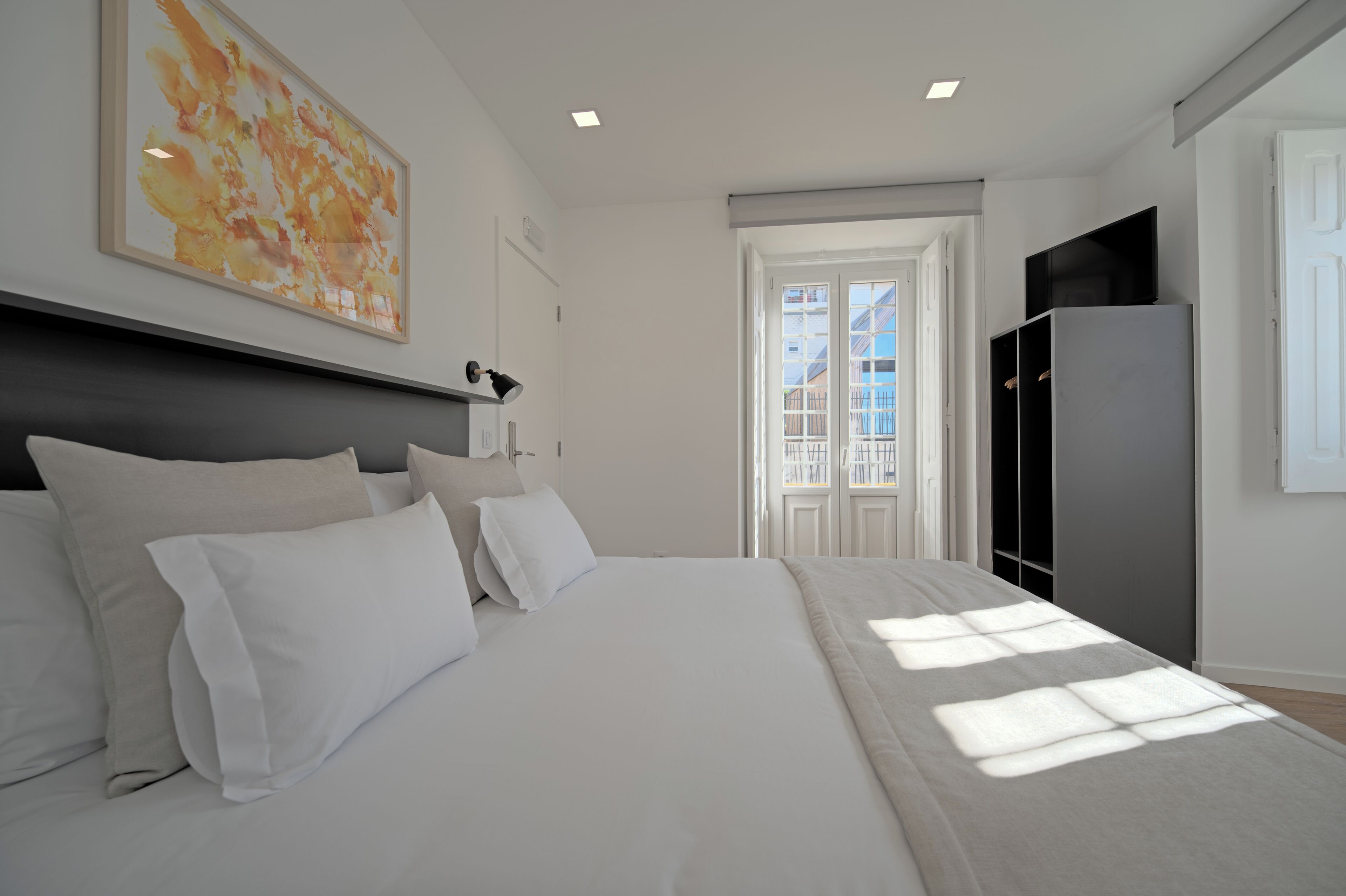 A bedroom with a bed, a nightstand, a desk, a chair, a wardrobe, and a window.