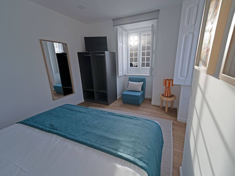 Un dormitorio con cama, armario, escritorio y ventana.