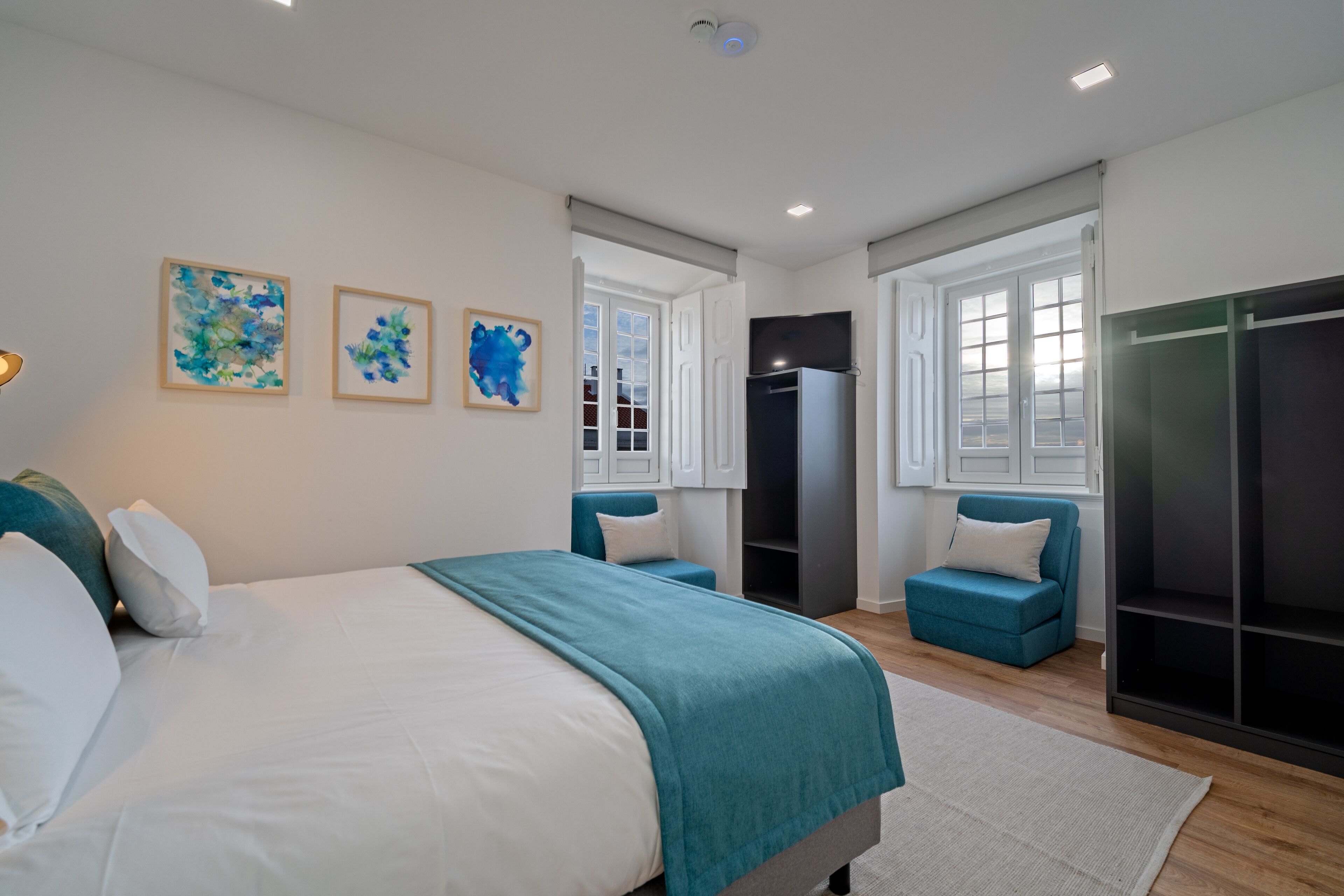 Een moderne slaapkamer met een groot bed, een kledingkast, een zithoek en kunst aan de muur.