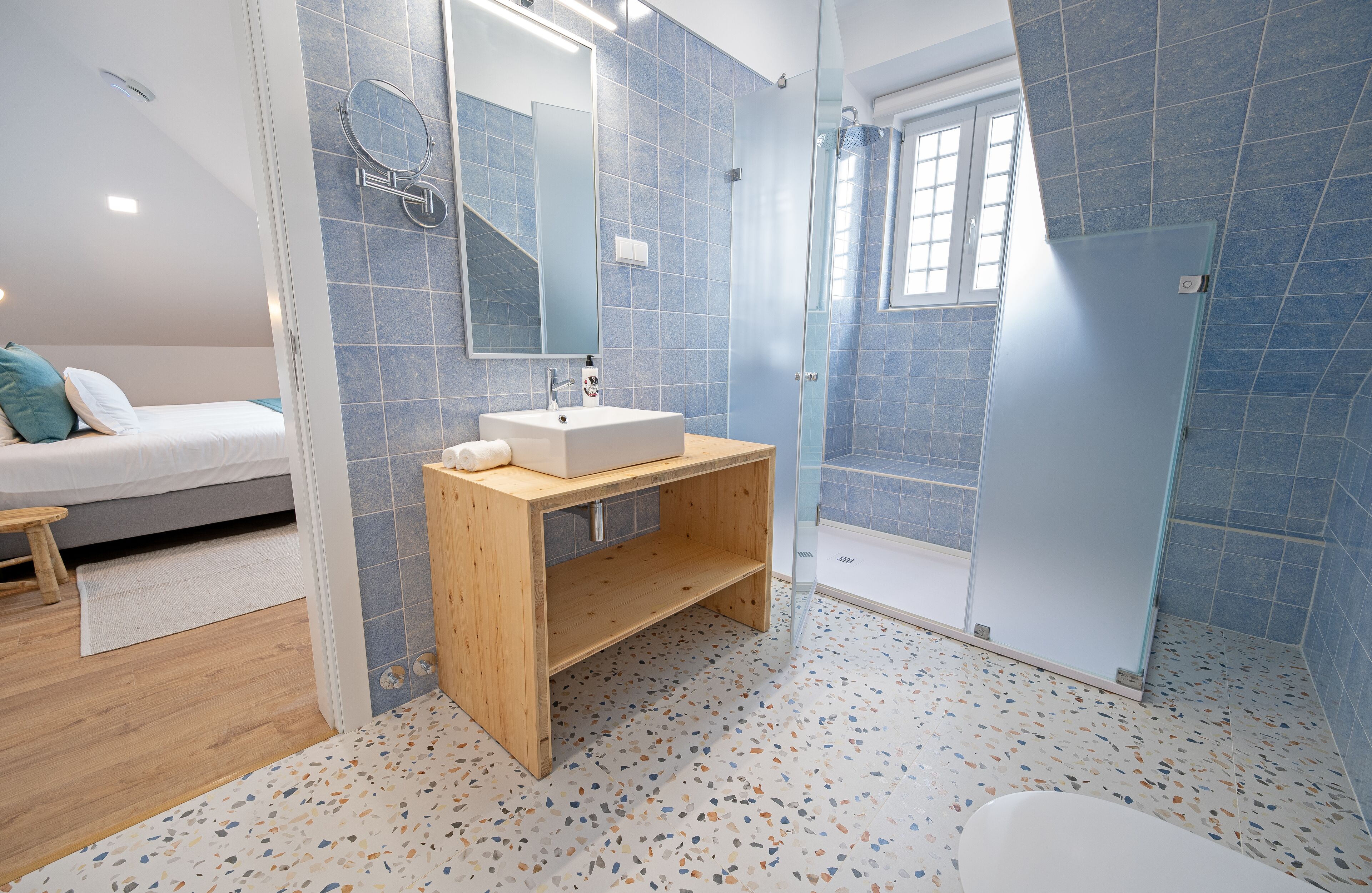 Un baño moderno con tocador de madera, un espejo grande y zona de ducha.