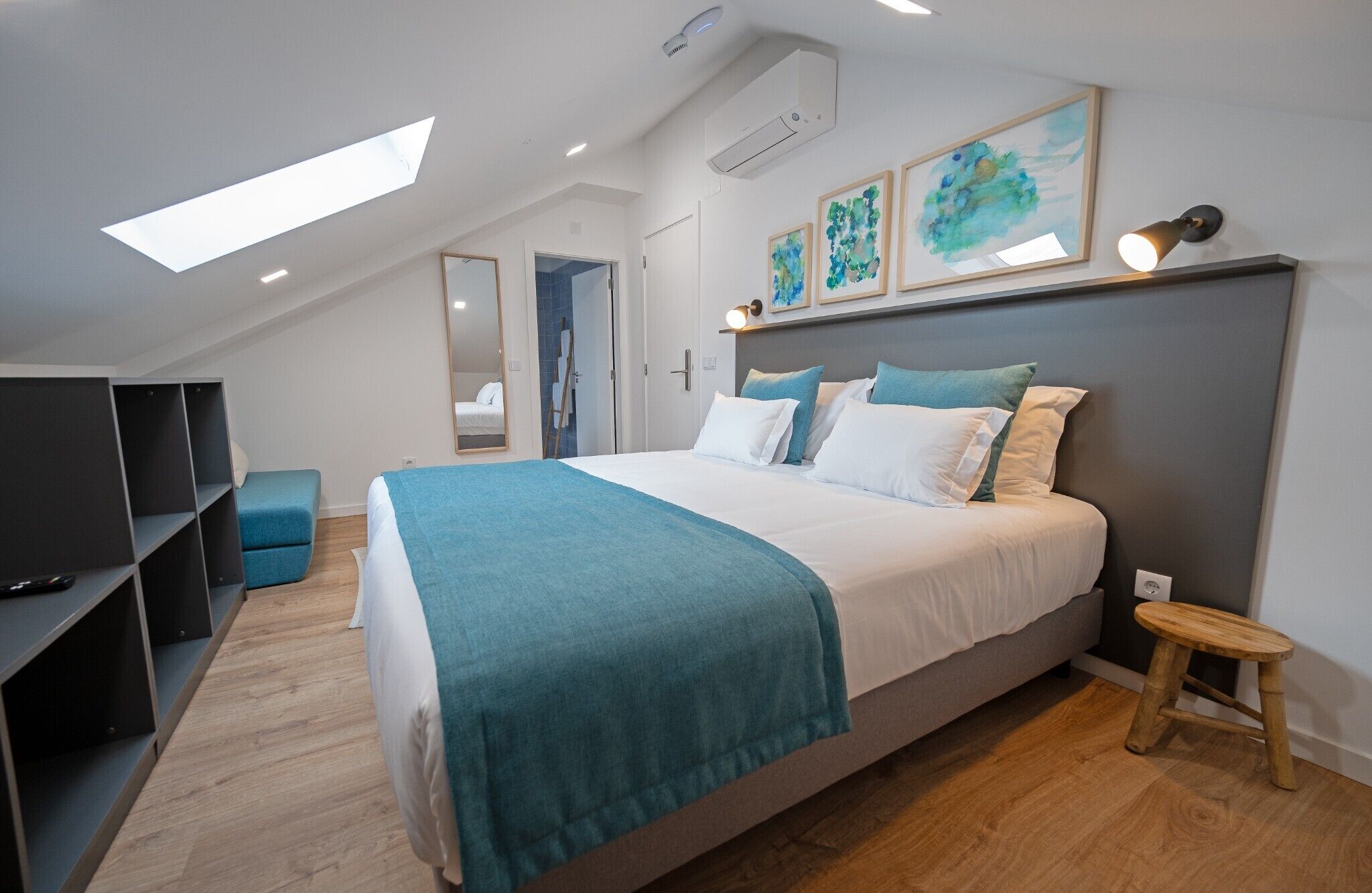 A bedroom with a bed, a TV, a desk, and a stool.