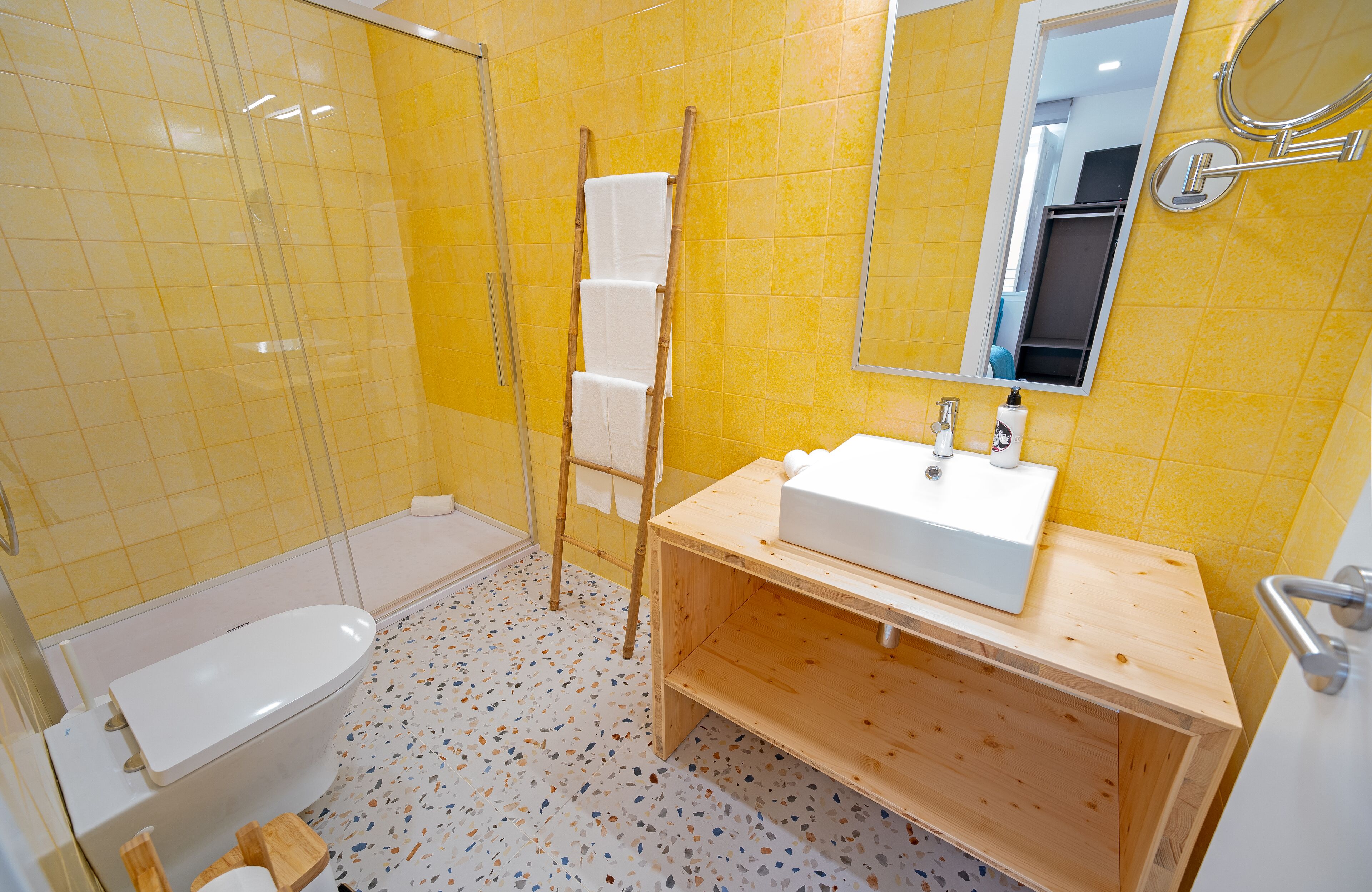 Un bagno con un water bianco, una toeletta in legno e uno specchio.