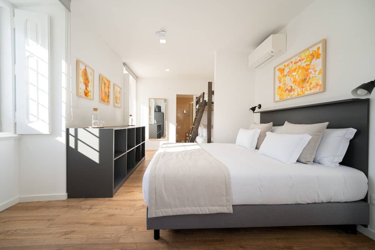 Ein Schlafzimmer mit einem Bett, einer Kommode, einer Leiter und Kunstwerken an den Wänden.