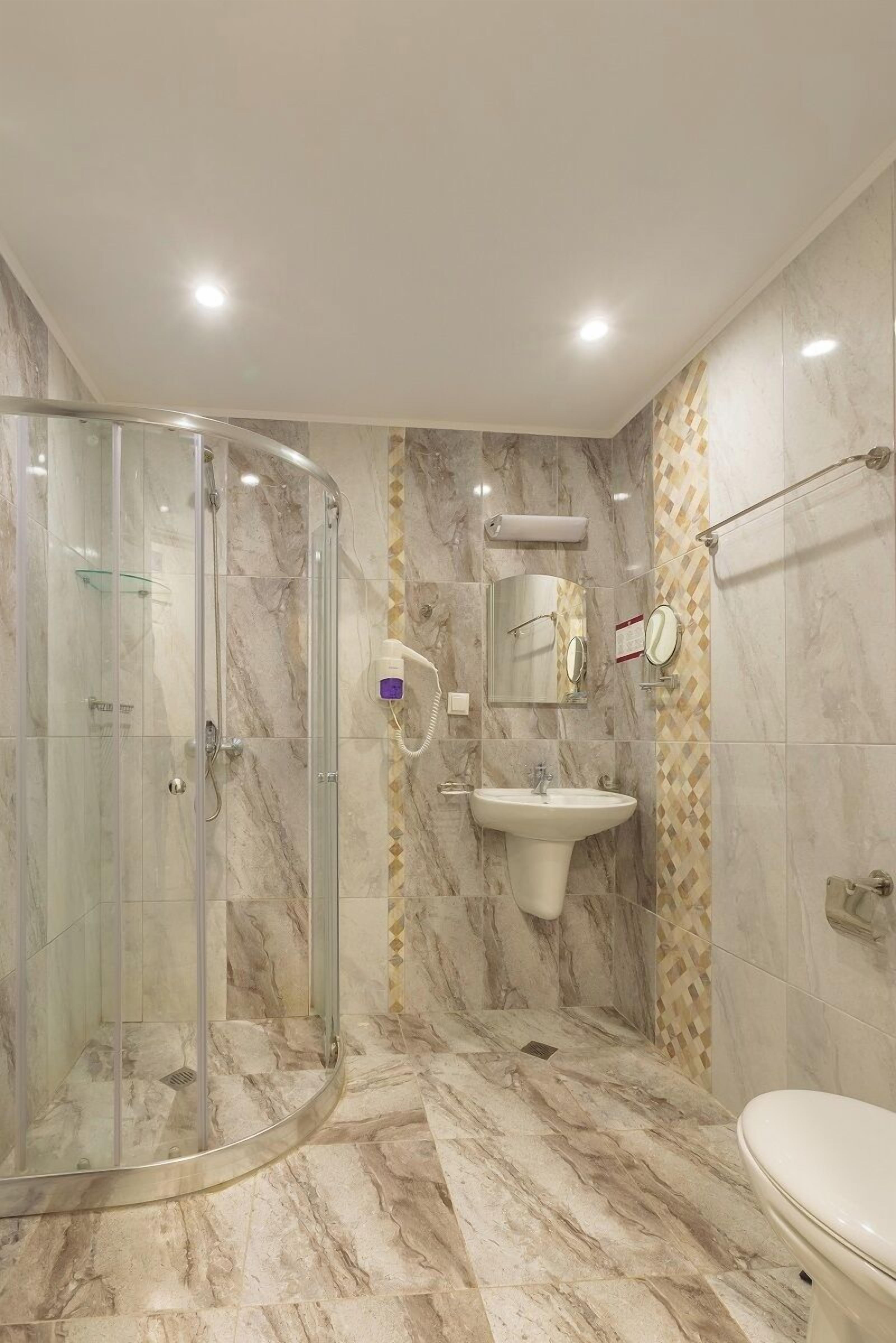 A modern bathroom with a glass shower enclosure, a sink, and a toilet.