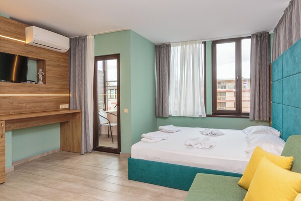 Une chambre d’hôtel avec un lit, une télévision, un bureau et un balcon.