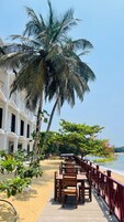 Un restaurante frente al mar con terraza, palmeras y vistas al océano.