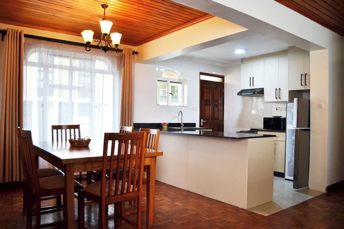 Een moderne keuken met een eethoek, houten plafond en witte kasten.