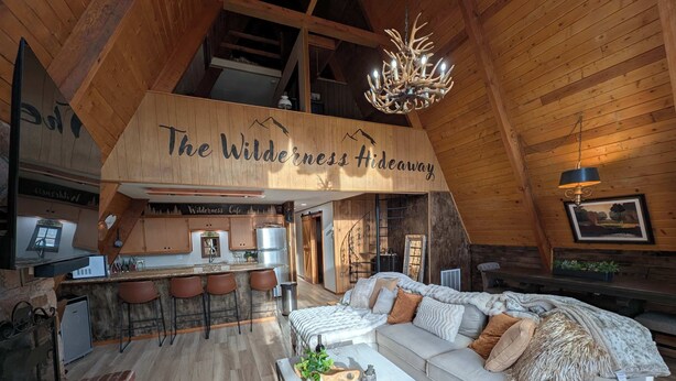 A cozy loft-style room with a kitchen, bar area, and a large sofa.