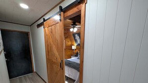 A room with a bed, a wooden door, and a ceiling fan.