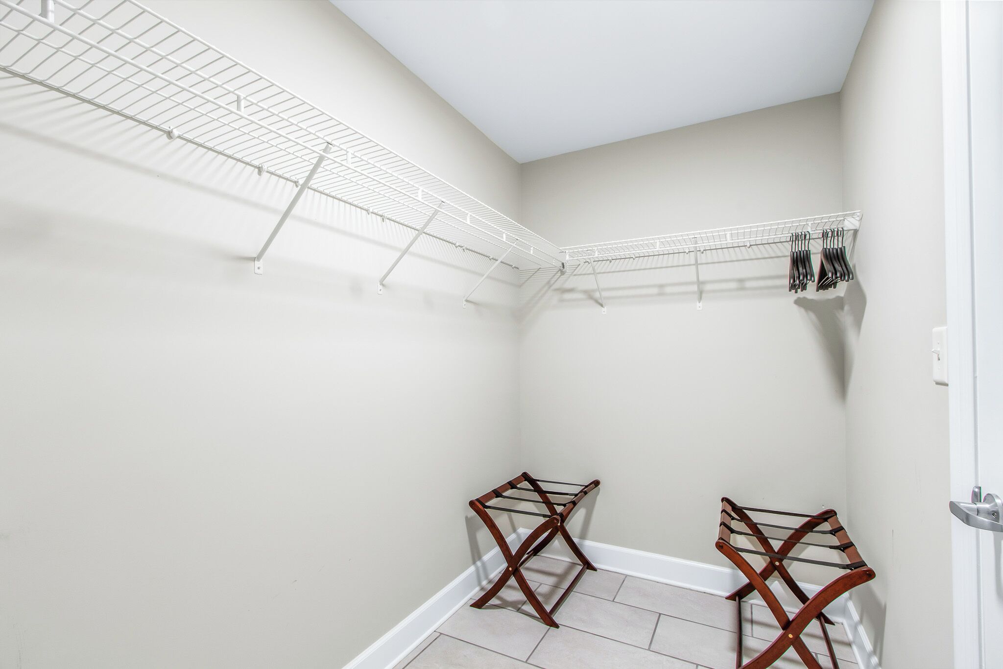 A laundry room with two wooden drying racks and a white metal drying rack.
