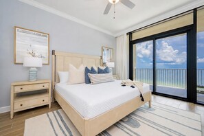 A bedroom with a bed, nightstands, a large window with a view, and a ceiling fan. - Fresh & Fabulous! New Condo Steps from the Gulf Shores Sand PGS2 1103 (Gulf Shores)