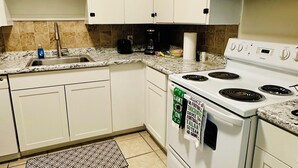 A kitchen with white cabinets, a stove, a microwave, and a sink. - Charming 2-Bedroom Condo in Baton Rouge close to LSU and Downtown (Baton Rouge)