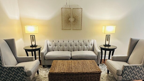 A living room with a grey sofa, two armchairs, a coffee table, a patterned rug, a ceiling fan, and two lamps. - Charming 2-Bedroom Condo in Baton Rouge close to LSU and Downtown (Baton Rouge)