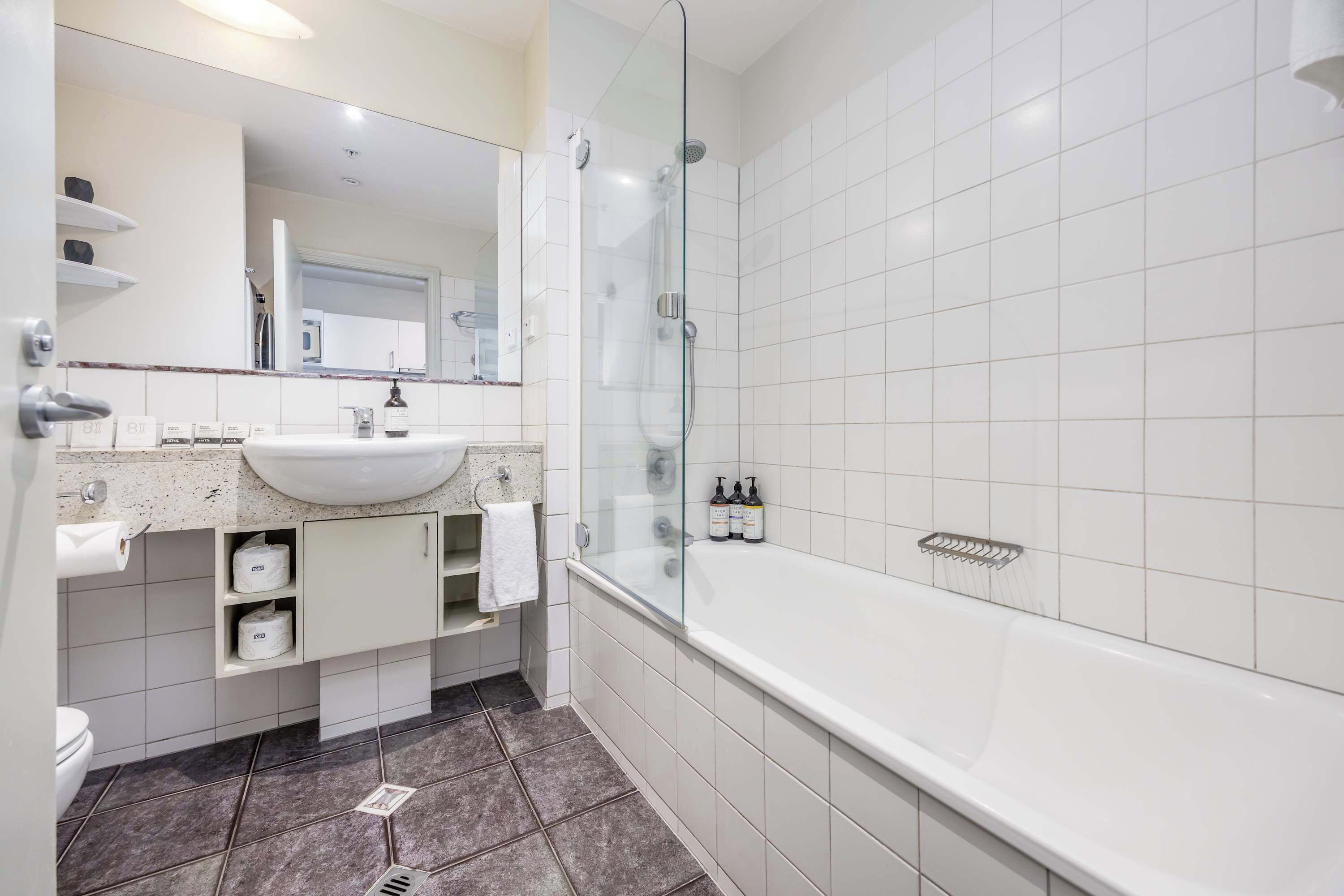 A modern bathroom with a glass-enclosed shower, a white sink, and a large bathtub.