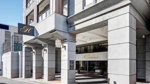 A hotel entrance with a prominent 'H' sign, a clear entryway, and a visible 'Heritage' sign. - City View Studio w Rooftop Pool, Gyms in CBD (Auckland)