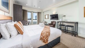 A hotel room with a large bed, a desk with two chairs, a TV, and a city view. - City View Studio w Rooftop Pool, Gyms in CBD (Auckland)