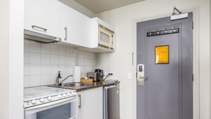 A compact kitchen with a stove, microwave, and refrigerator. - City View Studio w Rooftop Pool, Gyms in CBD (Auckland)