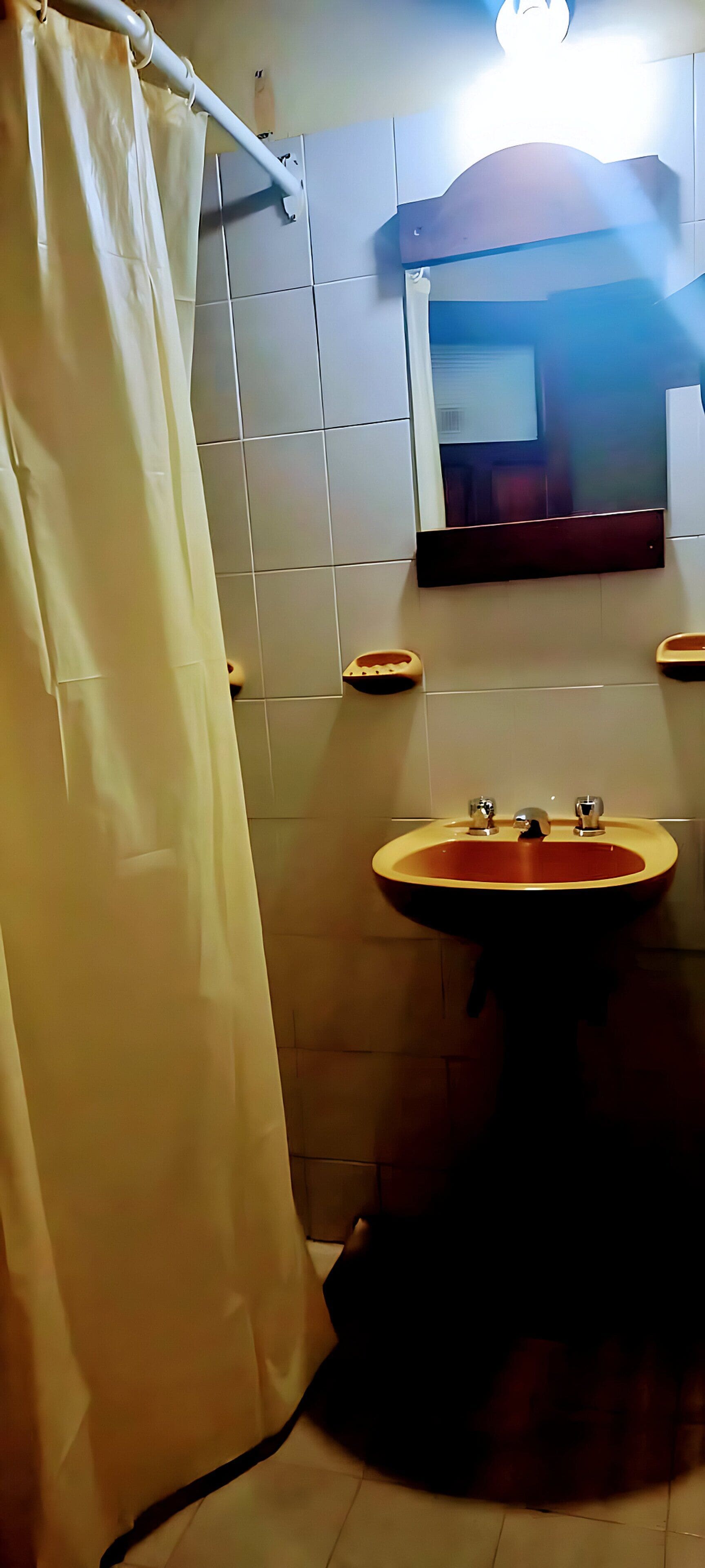 Een badkamer met een wastafel, spiegel en betegelde wanden.