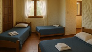 A room with two single beds, a wooden door, and a window with curtains.