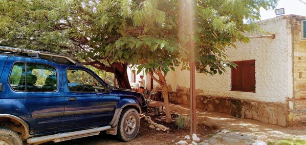 Un SUV azul estacionado junto a un edificio de fachada blanca y ventana roja.