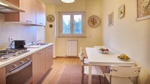 Cocina compacta con muebles de madera, estufa a gas y comedor con mesa y sillas.