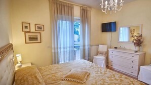 Una habitación de hotel con cama, cómoda, televisor y ventana con cortinas.