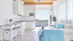 A modern kitchen with white cabinets, a dining area with a white table and chairs, and a balcony with a view. - The Italian Lady - Unit 1 (Alassio)