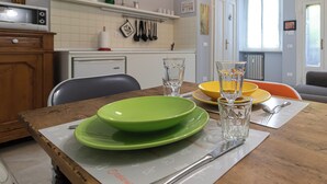 A dining table with a placemat, green and yellow plates, a glass, and cutlery. - Italianway Comfort - Rosmini 13 D (Milano)