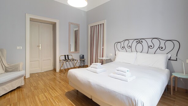 A hotel room with a large bed, a chair, a desk, and a mirror. - Italianway Comfort - Rosmini 13 D (Milano)