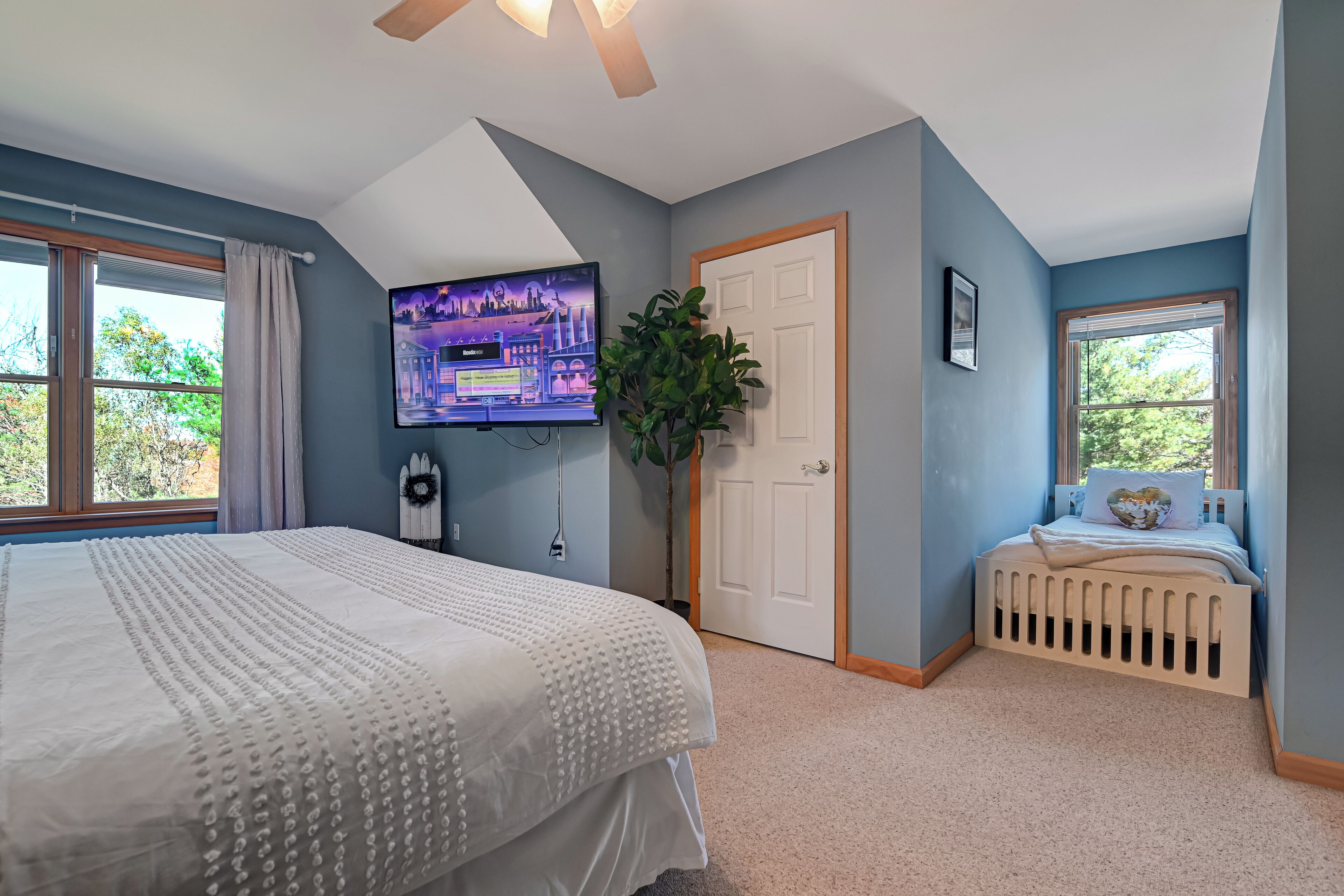 Un dormitorio con una cama grande, un televisor en la pared, una puerta y una ventana.