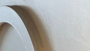Ein Detailaufnahme einer weißen Wand mit strukturierter Oberfläche und abgerundeter Kante.