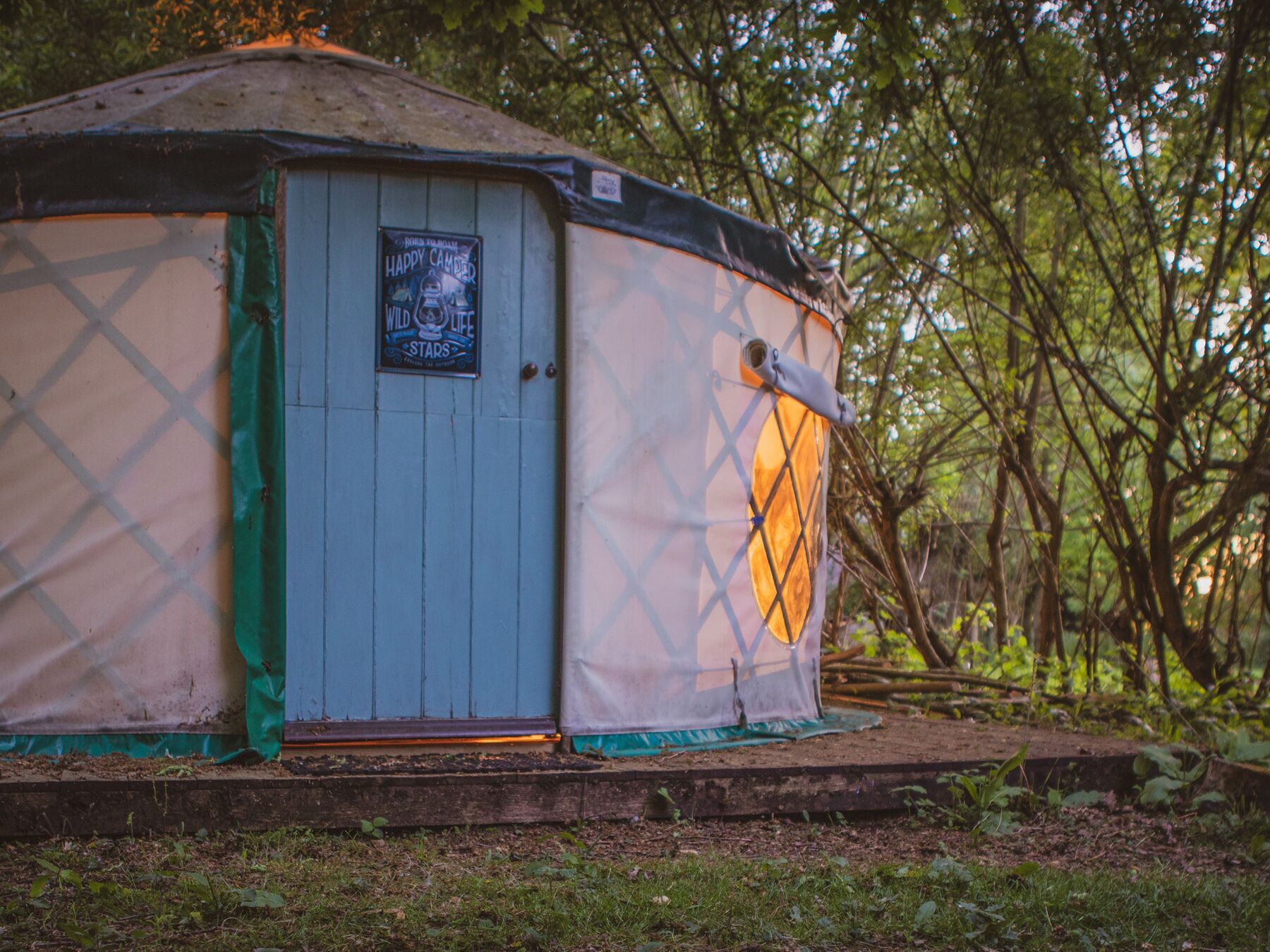 Una yurta con una puerta y un cartel, rodeada de árboles.