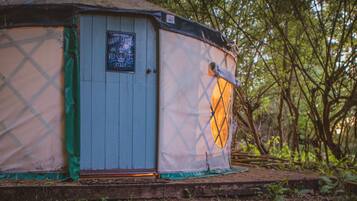 Una yurta con una puerta y un cartel, rodeada de árboles.