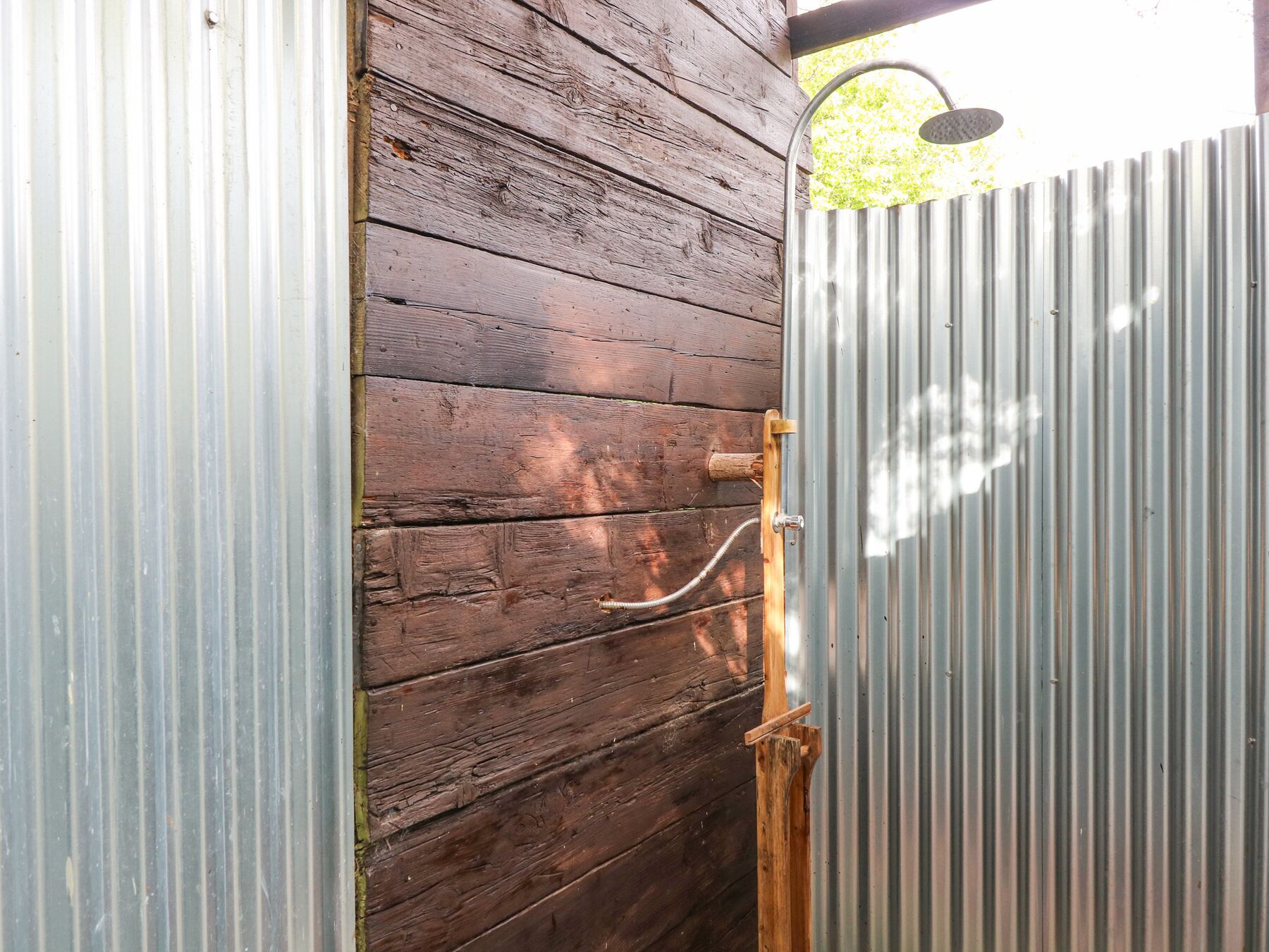 A wooden door with a metal latch and a hose attached to it.