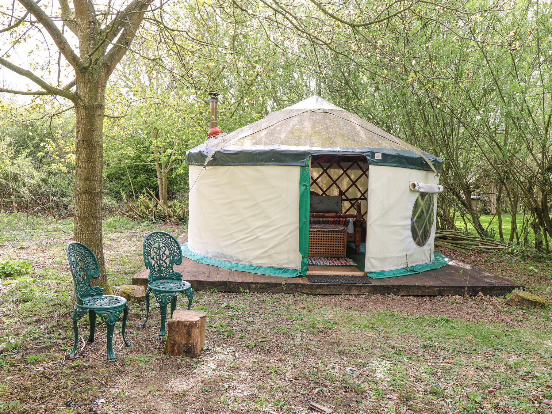 A yurt with a covered entrance, a bench, and a small table outside.
