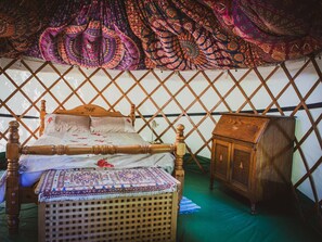 A traditional yurt with a wooden bed, a woven bench, and a cabinet. - Brandon House Farm Yurt (Norwich)